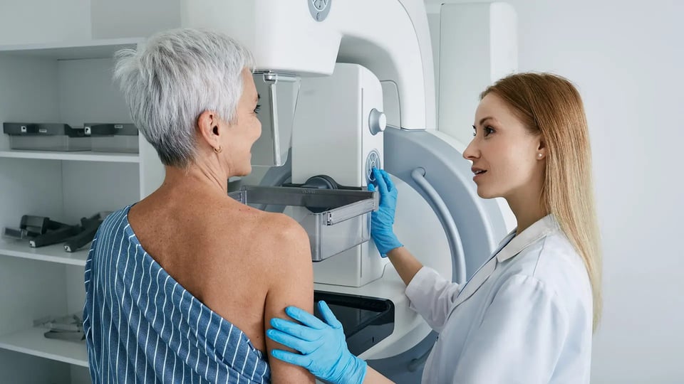 Senior woman having mammography scan at hospital with medical technician. Mammography procedure, breast cancer prevention